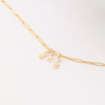 An Element Long Link Chain with three Petite Nameplate Pendants, 'lara', 'd' and 'livia', all in yellow gold on a white background. 