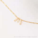 An Element Long Link Chain with three Petite Nameplate Pendants, 'lara', 'd' and 'livia', all in yellow gold on a white background. 