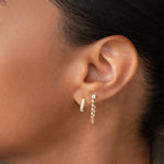 Close-up of woman's ear wearing a White Topaz Chain Earring and a Pave Huggie. 