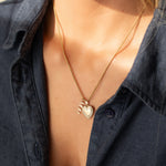 14k gold MUM word plate necklace with heart locket pendant worn on model.