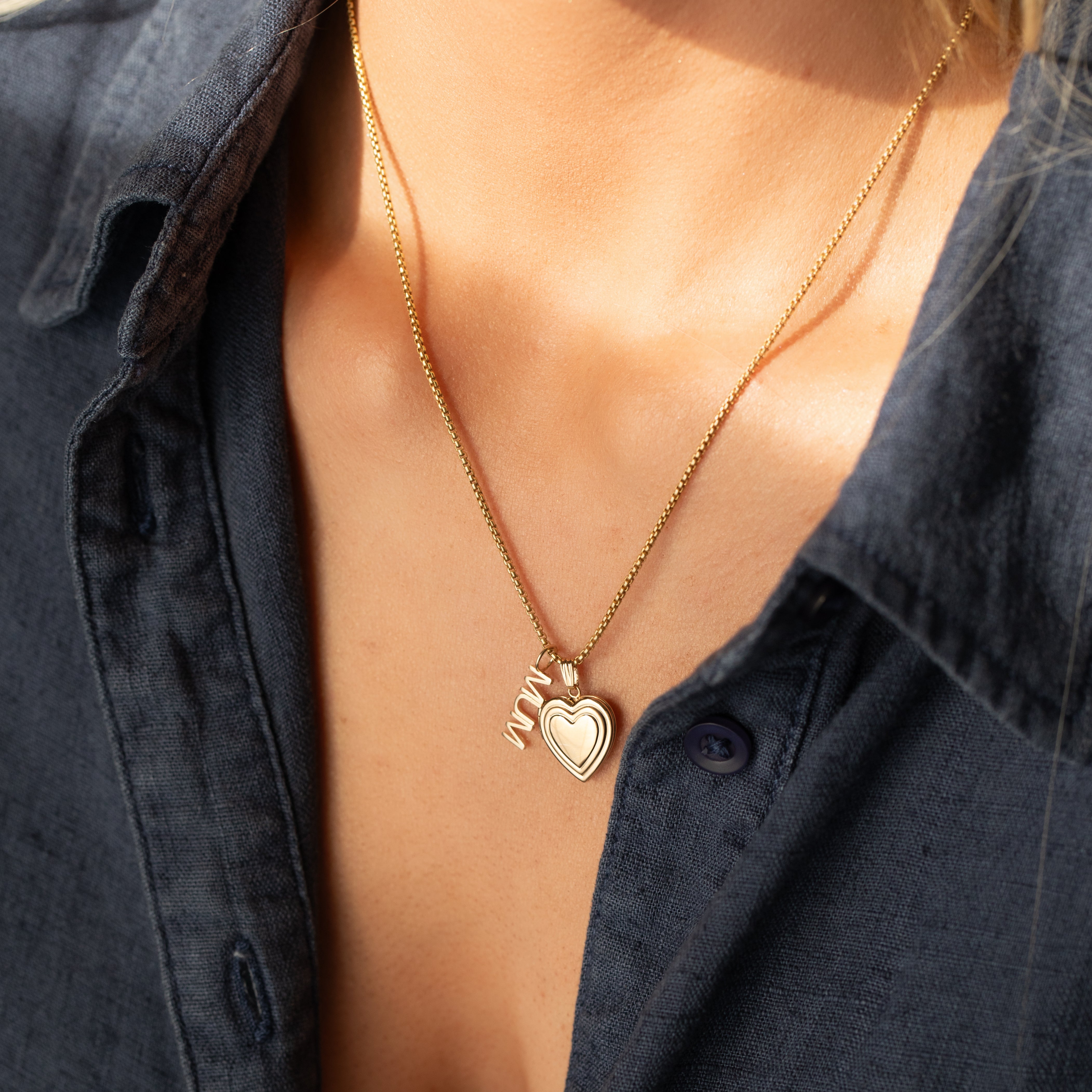 14k gold MUM word plate necklace with heart locket pendant worn on model.