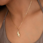 Close-up of a neck wearing a Golden Spiral Shell on The Slide Chain with a light brown strap top. 