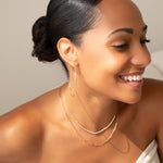 A woman wearing a Sleek & Chic Hoop - Large, an Element Short Link Chain and The Everyday Diamond Necklace with black hair against a light grey background. 