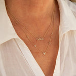 Close-up of a neck wearing a Pavé GAGA Necklace and a Custom Gold Necklace - 5 Letters, both in yellow gold, with a white shirt.