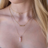 Close-up of a blonde woman's neck wearing a LOVE Necklace, AMOUR Necklace and The Love Retreat Necklace. 