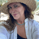 Maya Brenner wearing an Endless Summer Necklace - Sea + Sky, a Bold Link Chain and a Custom Gold Necklace - 5 Letters, styled in a white shirt and straw hat. 