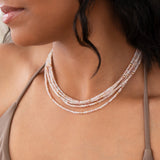 Close-up of a woman's neck wearing several Endless Summer Necklaces in Pink Sands, styled with a taupe strap top. 
