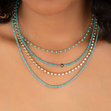 Close-up of a neck wearing The Bluebell Bouquet Necklace, Endless Summer Necklaces in Turqs + Caicos and Santorini, and The Ultimate Diamond Necklace.