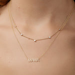 A neck wearing a Quintet Diamond Layering Necklace and a Mama Necklace, both in yellow gold. 