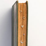 book jewelry display with various small jewelry items on a white background