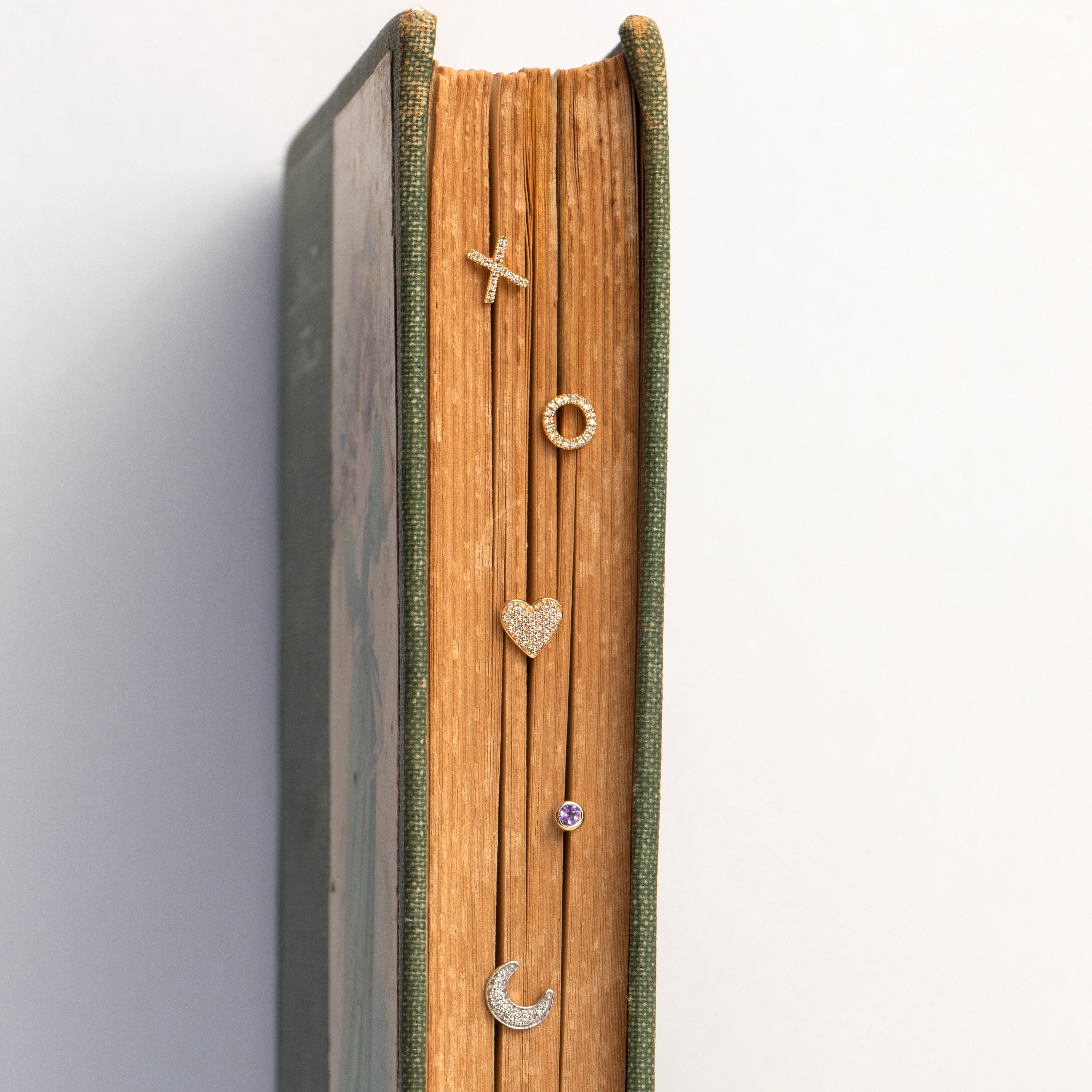book jewelry display with various small jewelry items on a white background