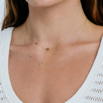 Close-up of a person wearing a delicate gold necklace with small charms.