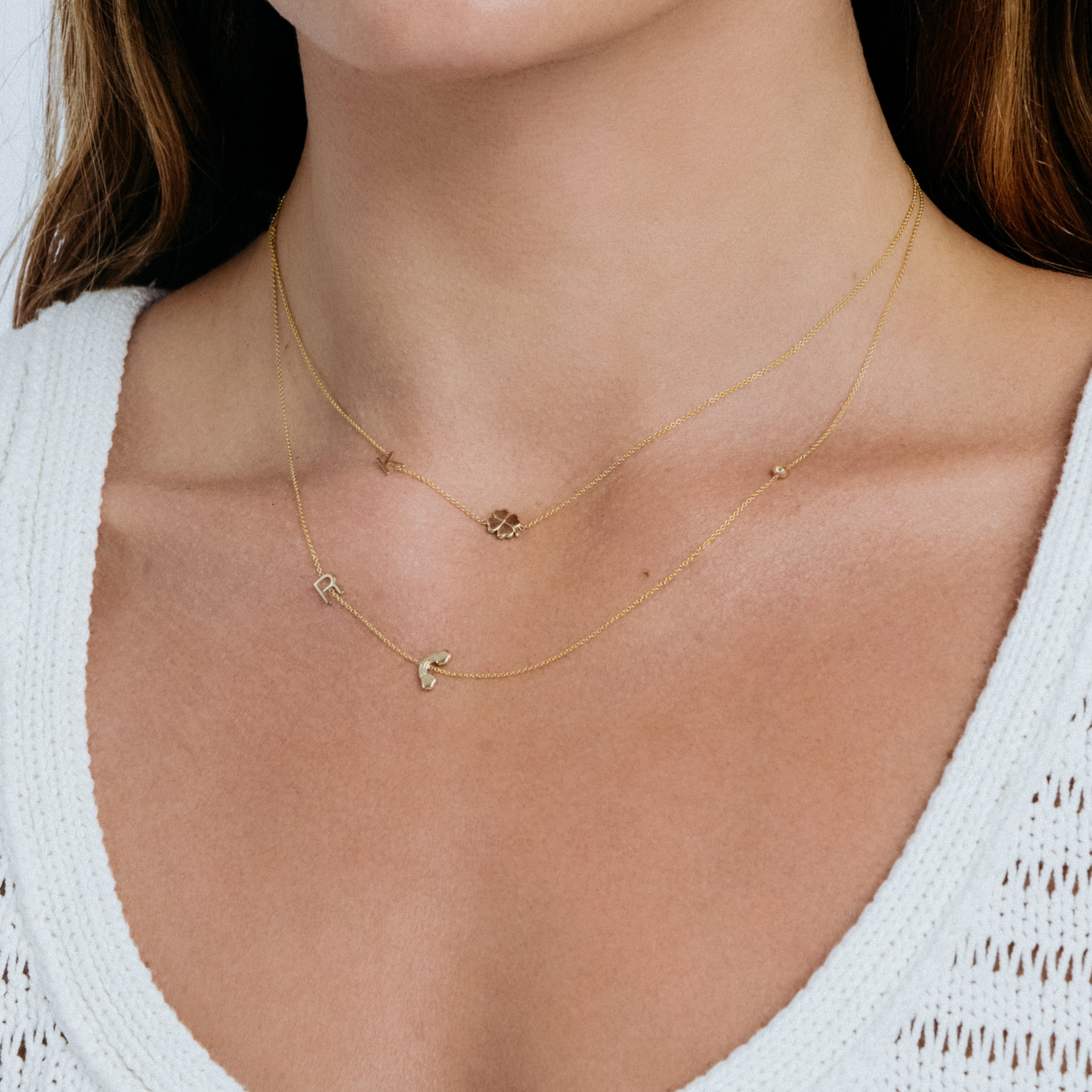 Close-up of a person wearing a delicate gold necklace with small charms.