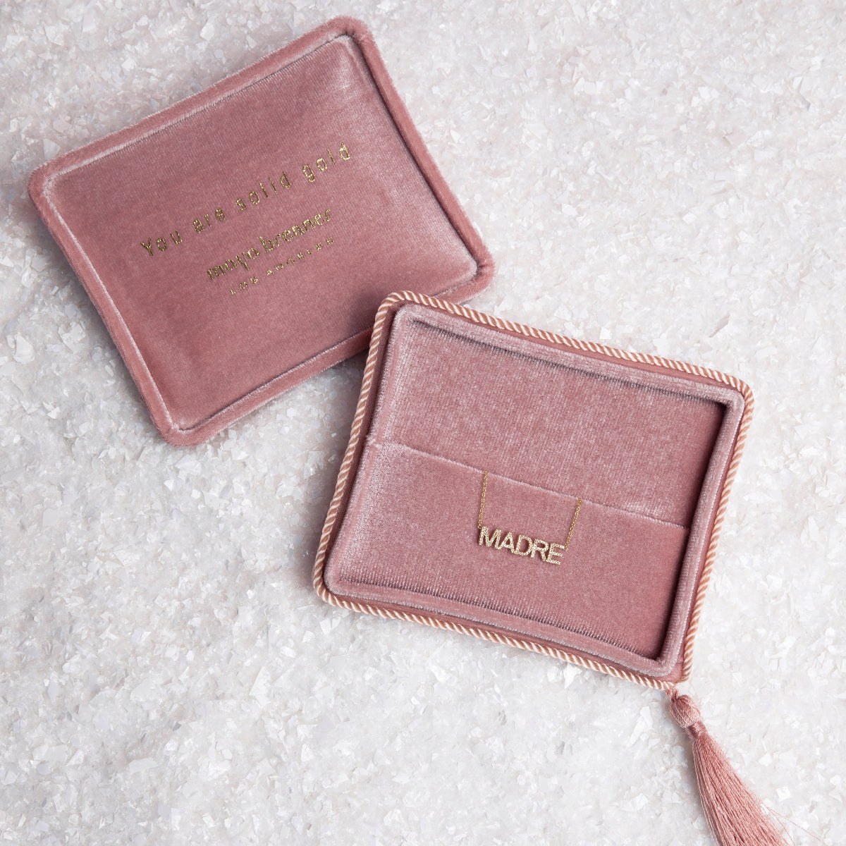Two pink velvet jewelry boxes with a Pavé Madre Necklace on a textured off-white background. 