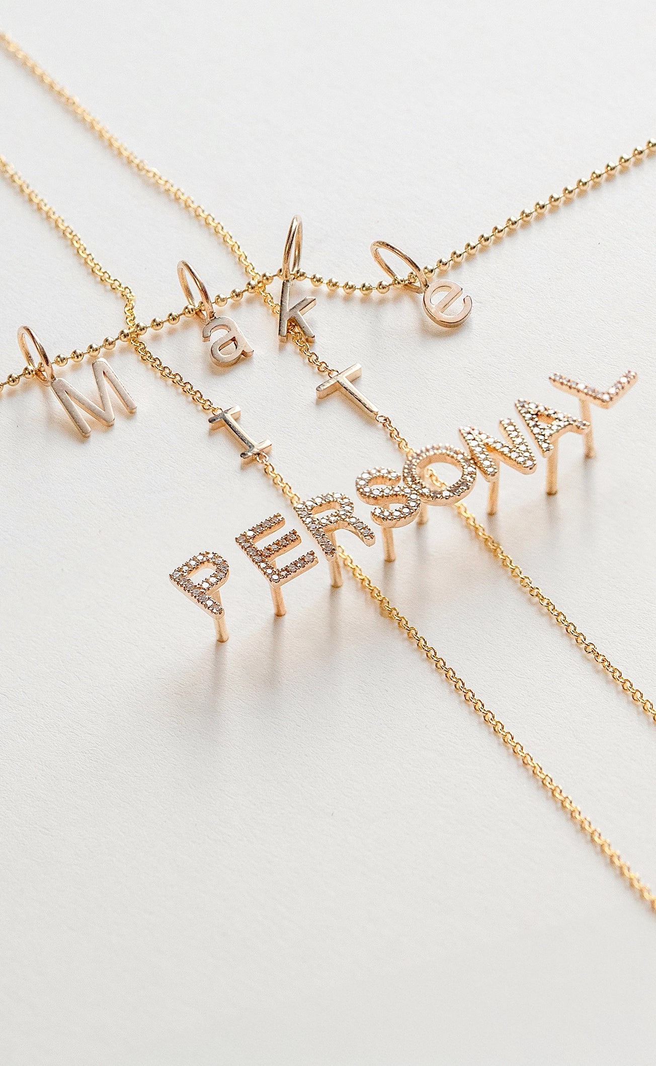 Gold necklaces with letter pendants on a light background