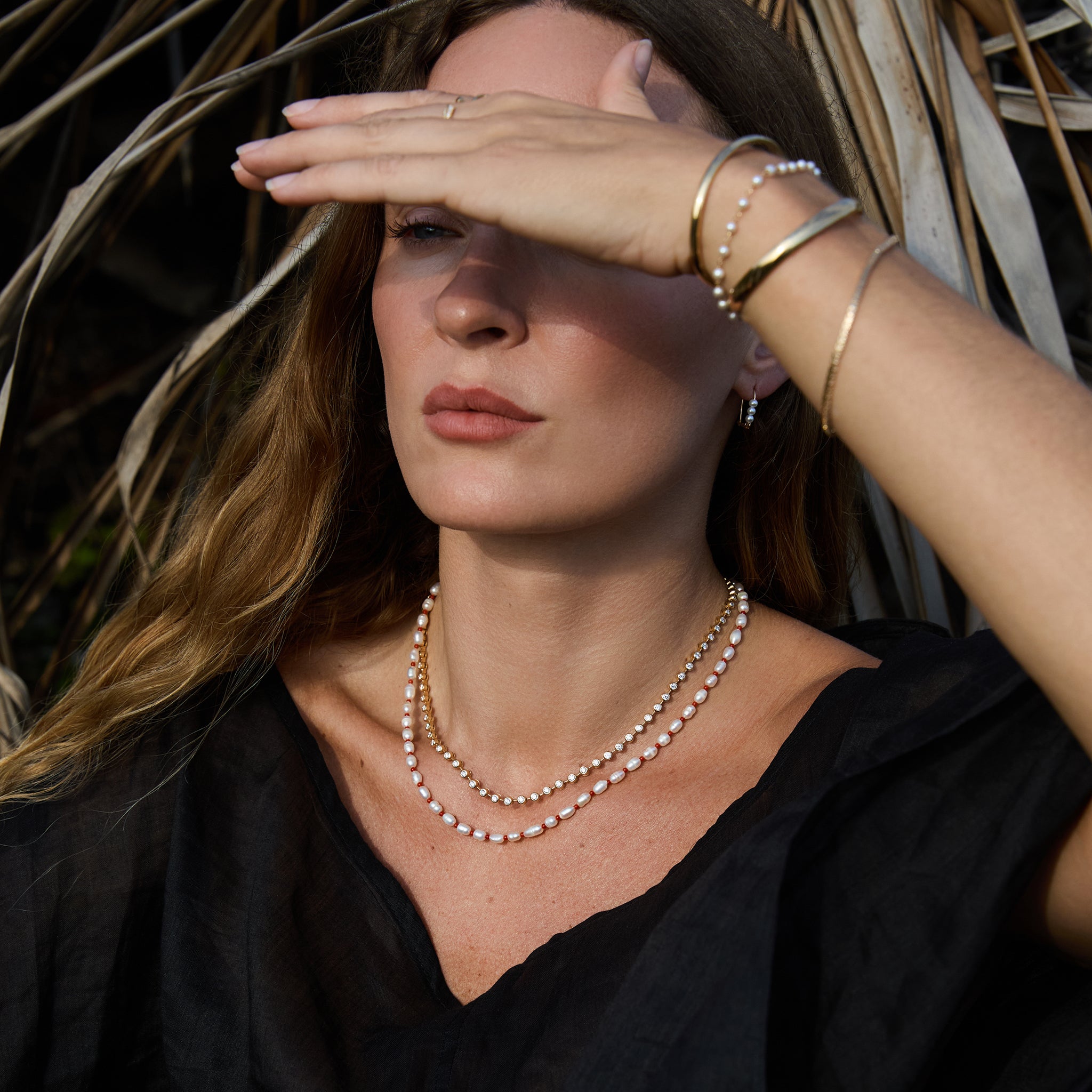 Model wearing Maya Brenner Cabana Pearl Necklace layered with the Ultimate Diamond Necklace, styled with gold cuff bracelet and pearl bracelet