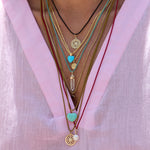 Color Cord Necklaces with multiple pendants on model wearing a pink shirt.