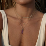 Model wearing the Element Short Link Chain with a Balance Crystal Charm and layered diamond necklaces.