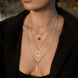 Model wearing the Baroque Pearl Pendant on a gold chain layered with gold charm necklaces.