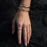 Model wearing the Lily Bouquet Bracelet layered with gold and diamond bracelets.