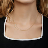 Gold necklaces with star charms on a person wearing a black top with white trim.