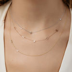 Layered initial necklaces on a model wearing a beige top