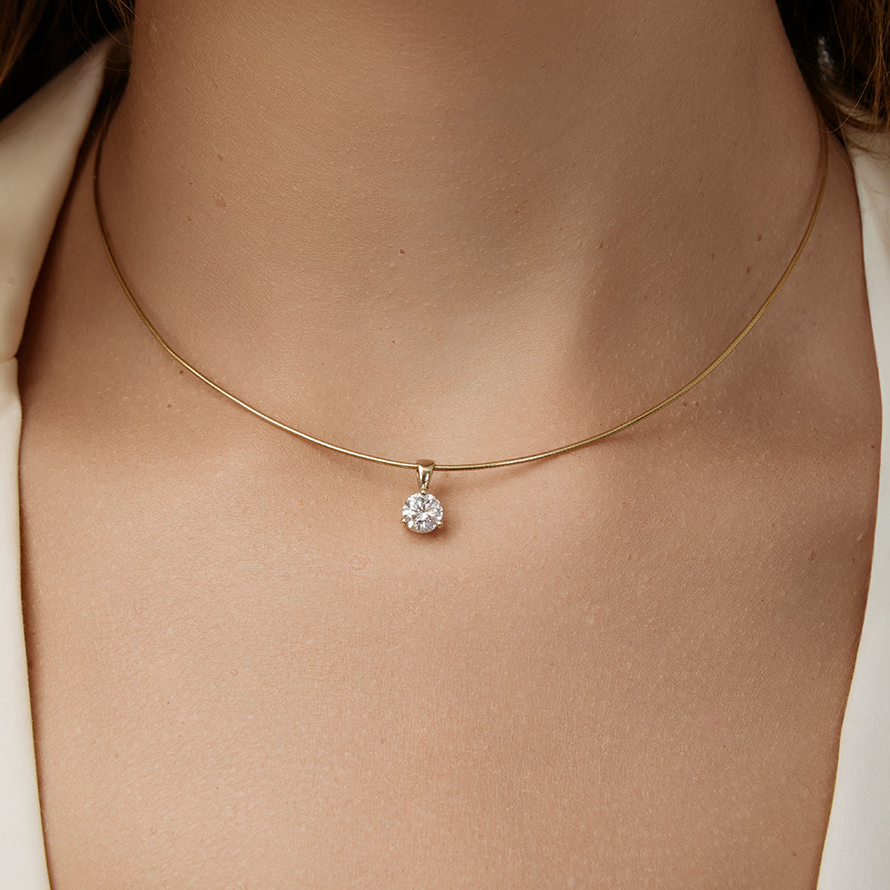 Gold necklace with a diamond pendant on a person's neck