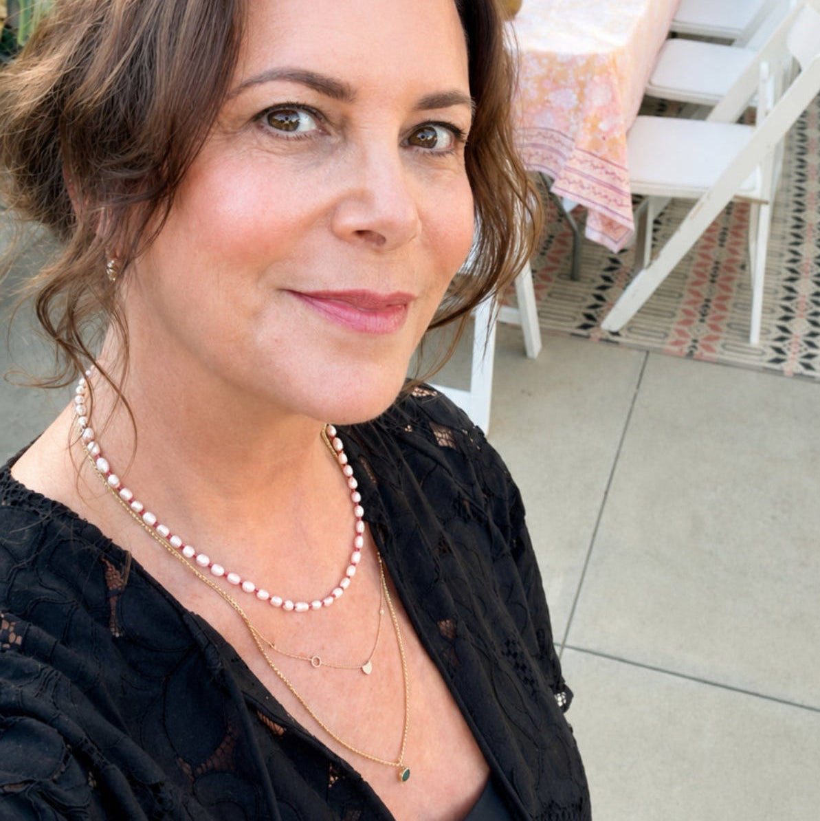 Maya Brenner wearing the Cabana Pearl Necklace layered with delicate gold necklaces at an outdoor gathering