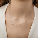 Two dainty white gold necklaces with gold and diamond heart charms layered together.