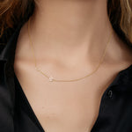 Asymmetrical gold necklace with  two initials on a model wearing a black shirt