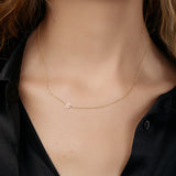 Asymmetrical gold necklace with  two initials on a model wearing a black shirt