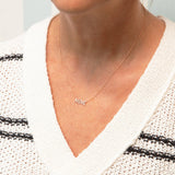 Close-up of a décolletage wearing a MIMI Necklace in rose gold with a cable chain, and a white knit with black horizontal stripes. 