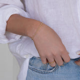 Close-up of a woman’s arm wearing a Mini Bubble Bracelet, two Delicate Beaded Bands and a Twinkle Twinkle Ring, with a white shirt and light blue jeans.