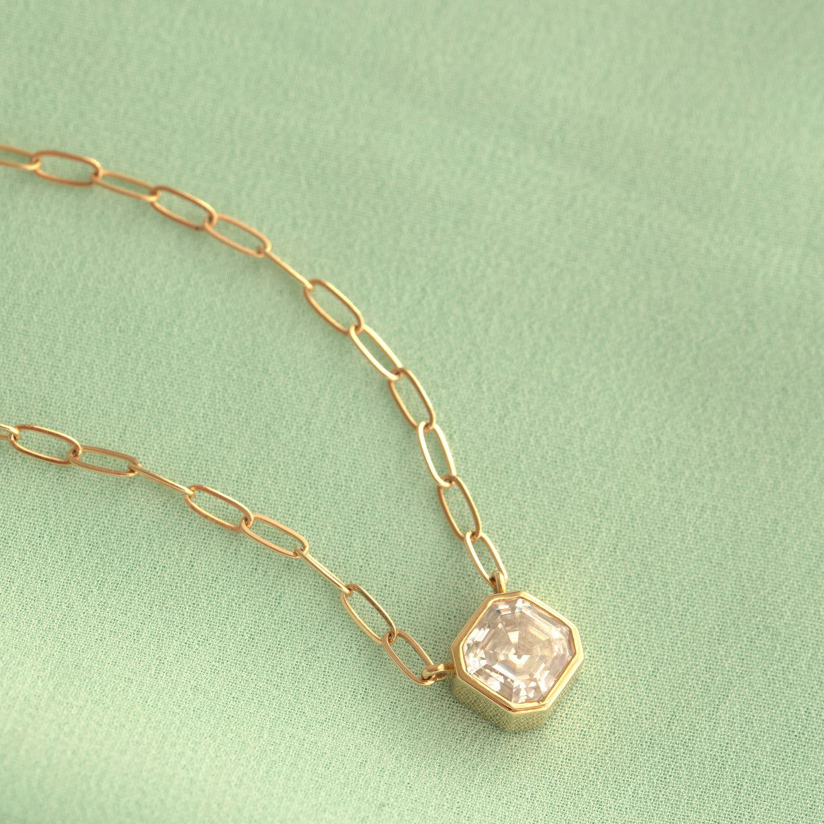 A C'est Moi Deco Necklace in yellow gold against a light green background. 