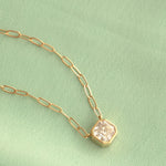 A C'est Moi Deco Necklace in yellow gold against a light green background. 