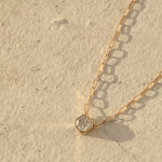 A C'est Moi Deco Necklace in yellow gold on a cream textured background. 
