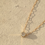 A C'est Moi Deco Necklace in yellow gold on a cream textured background. 
