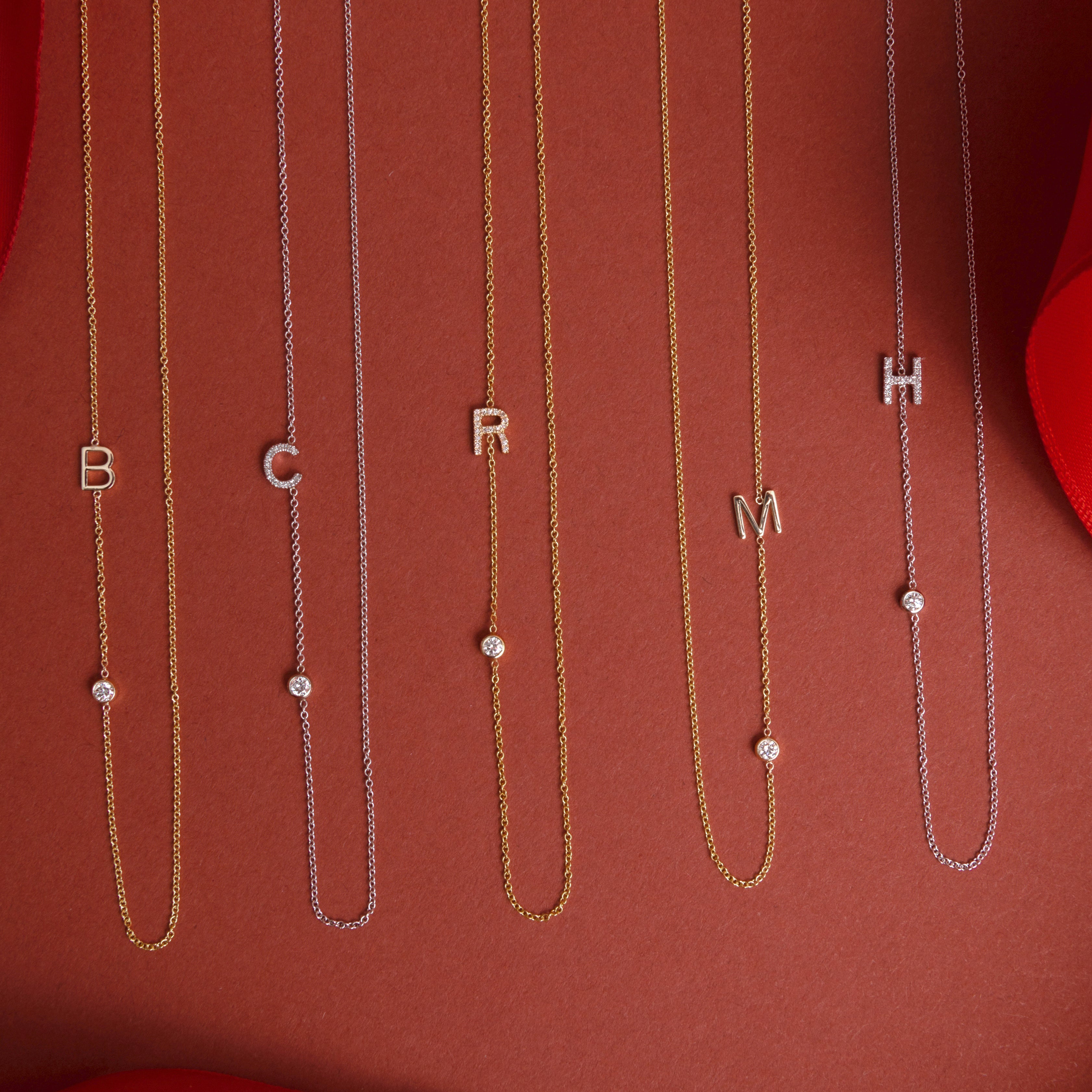 Gold necklaces with letter charms on a red background