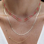 Three necklaces worn on a person's neck with a plain background