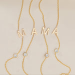 Gold necklace with 'MAMA' letters and small diamonds on a beige background