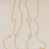 Gold necklace with 'MAMA' letters and small diamonds on a beige background