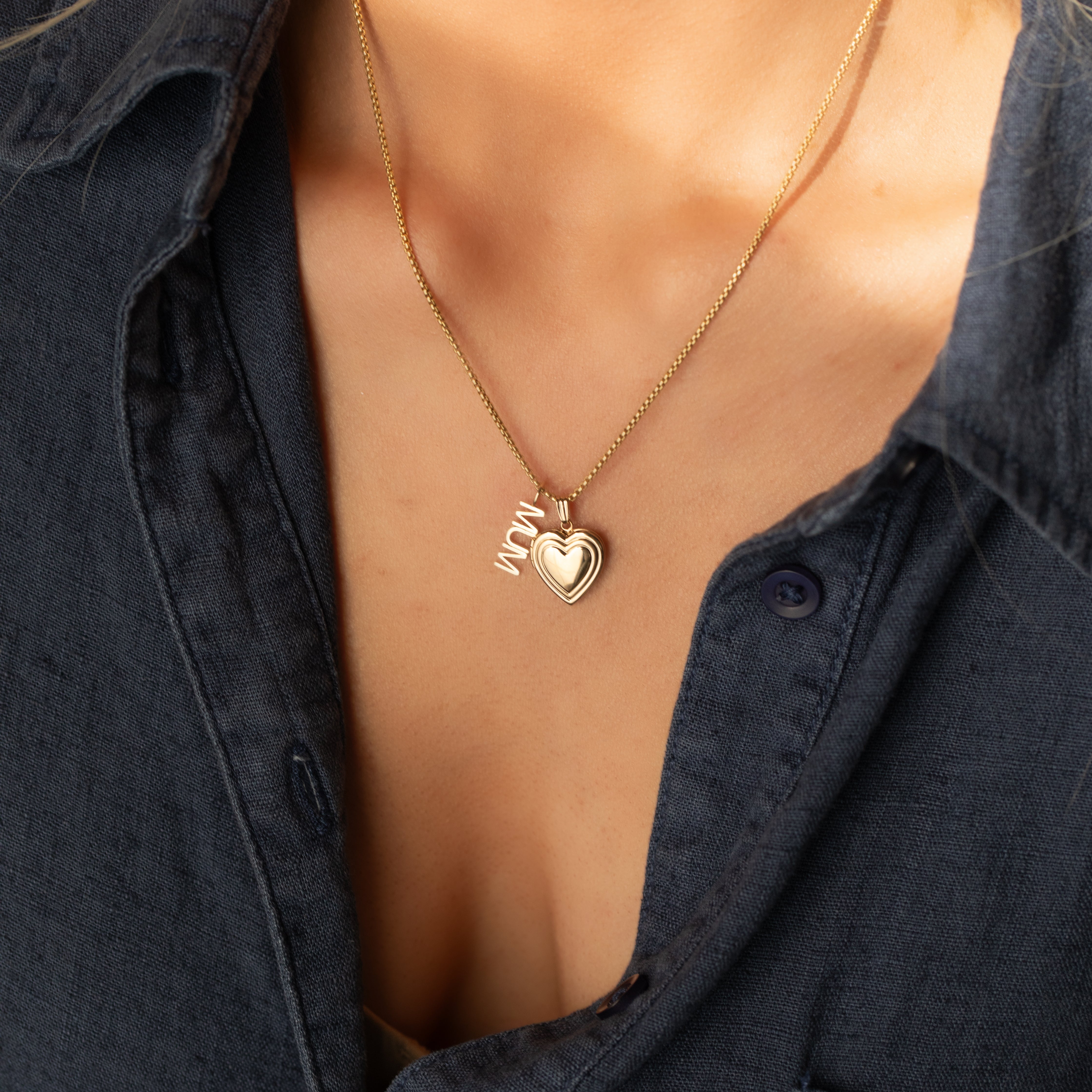 14k gold MUM word plate charm necklace styled with heart locket pendant on model.