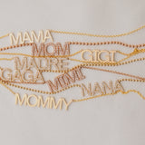 A MAMA Necklace, GIGI Necklace, Pavé MADRE Necklace, Pavé GAGA Necklace, Pavé NANA Necklace, and a MOMMY Necklace in yellow gold, along with Pavé MOM and MIMI Necklaces in rose gold, laid on an off-white background.