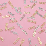 Yellow gold and white gold word plate pendants, some pavé, featuring MOM, MIMI, MAMA, NANA and GIGI, displayed on a pink background.