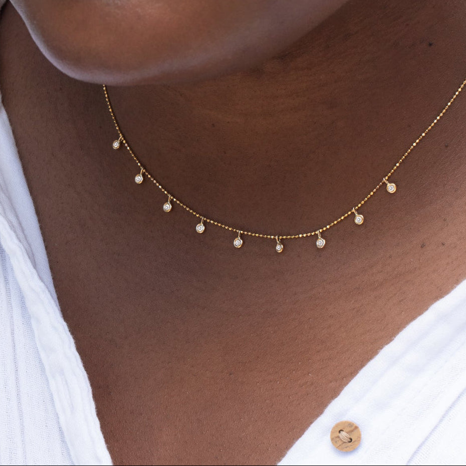 Close-up of a person's neck wearing a Stardust Diamond Necklace with a white shirt. 