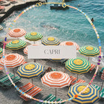 An Endless Summer Necklace - Capri against a beach background with colourful umbrellas and the word 'CAPRI' in the centre. 