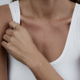 Close-up of a woman wearing a yellow gold Custom Gold Necklace - 1 Letter and Custom Gold Bracelet - 1 letter with the number 5, and a Lucky Number Ring with the number 1 with a white tank top.