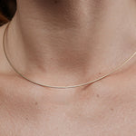 Close-up of a thin gold necklace on a person's neck