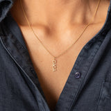 Gold necklace with 'GAGA' pendant worn by a person in a dark shirt.