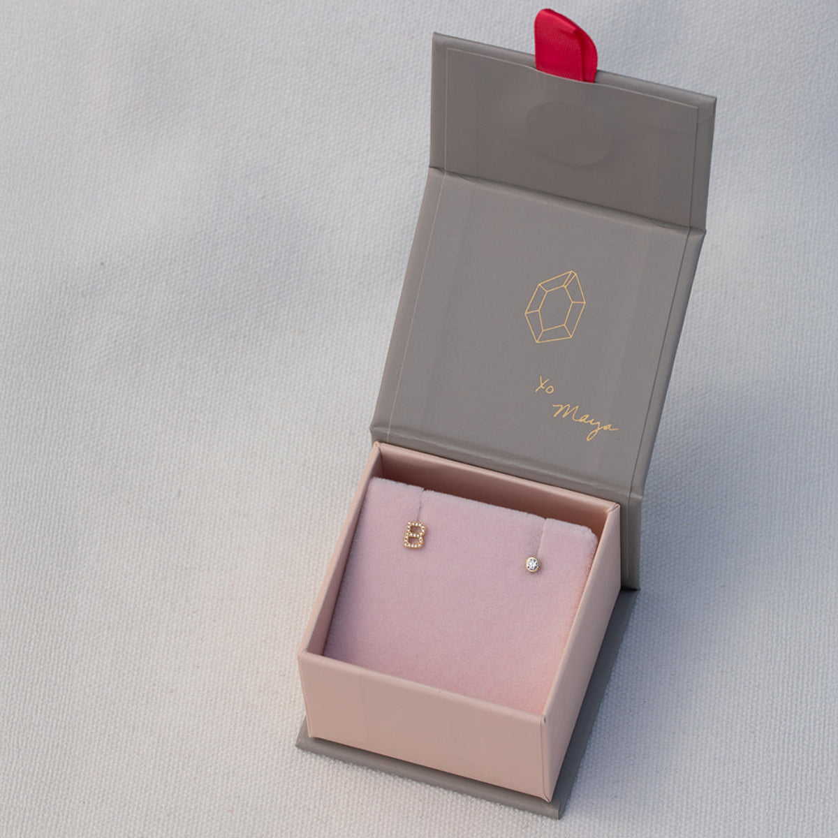A Pavé Monogram Earring Set in the letter B in a Maya Brenner jewellery box against a light grey background. 